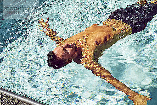 Eine Draufsicht auf einen Mann  der in einem Pool schwimmt.
