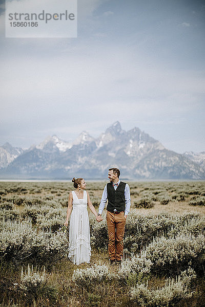 Glücklich lächelndes frisch vermähltes Brautpaar steht vor dem Grand Teton