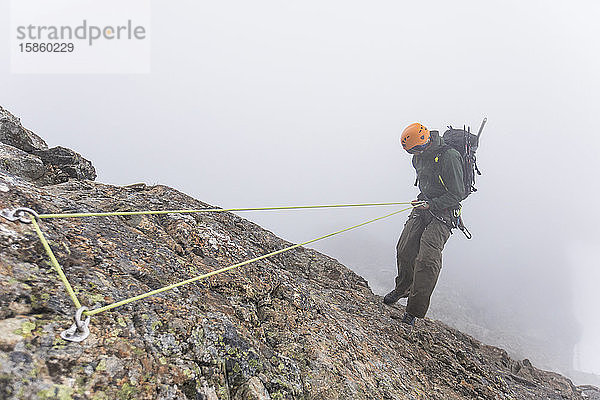 Draufsicht eines Bergsteigers beim Abseilen am Berghang.