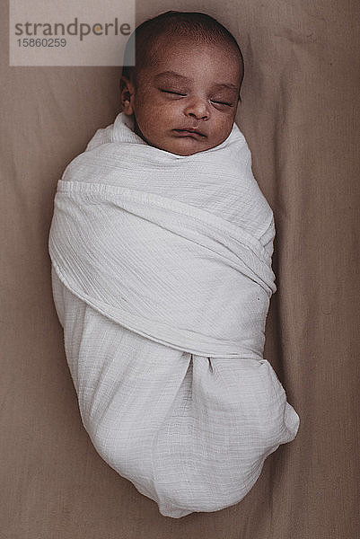 Schlafender gewickelter multirassischer Neugeborener
