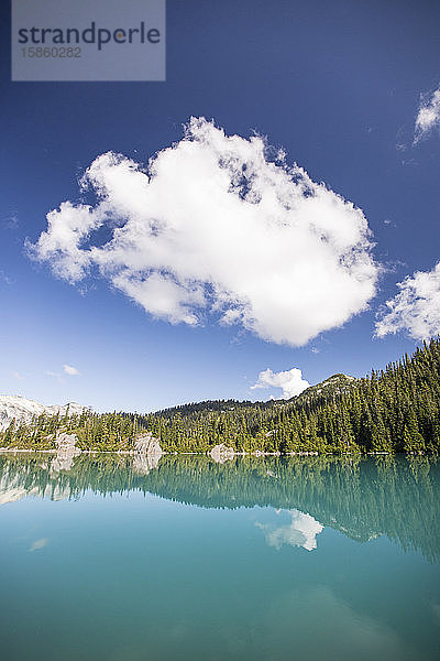 Reflexionen eines ruhigen blauen Sees und eines Bergwaldes.