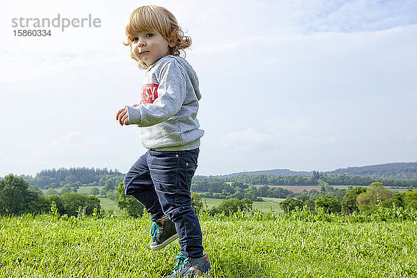 ein kleiner Junge  der sich auf einer grünen Wiese auf dem Land amüsiert  Caurel Bretagne  Frankreich.