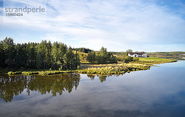 Idyllische Flusslandschaft mit Laubwald und einsamem Landhaus an sonnigen Sommertagen