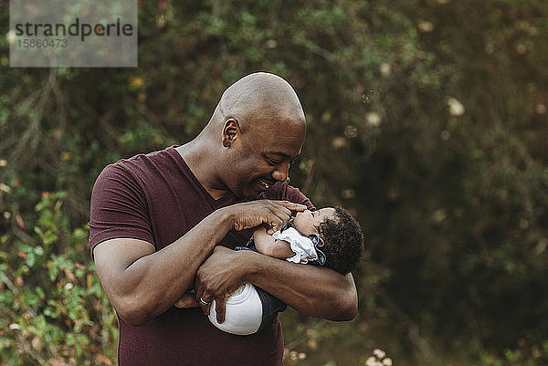 Nahaufnahme eines glücklichen Vaters  der ein Neugeborenes hält und es anlächelt