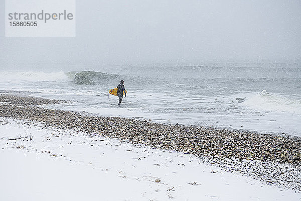 Mann geht im Winterschnee surfen