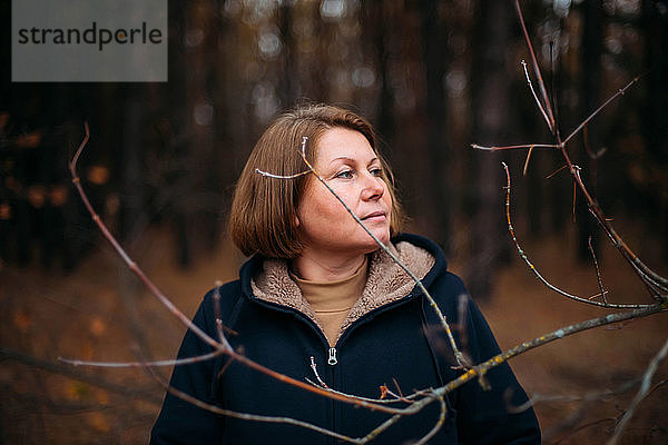 Nahaufnahme-Porträt einer im Wald stehenden Frau