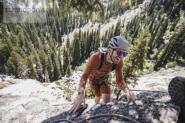 Ein junger Mann lächelt beim Felsklettern in den Tetons  Wyoming