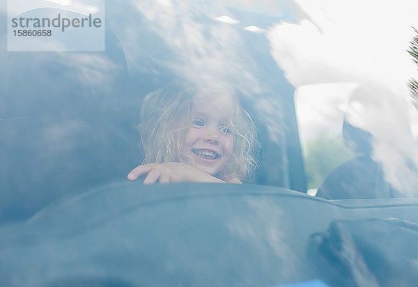 Porträt eines jungen Mädchens  das lächelnd in einem Auto auf dem Fahrersitz sitzt