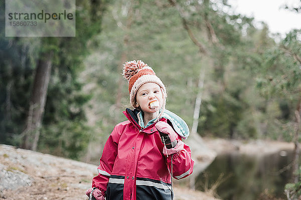 junges Mädchen isst Marshmallows beim Camping in einem Wald in Schweden