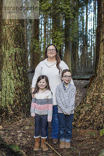 Porträt einer Mutter mit ihren beiden Kindern im Wald.
