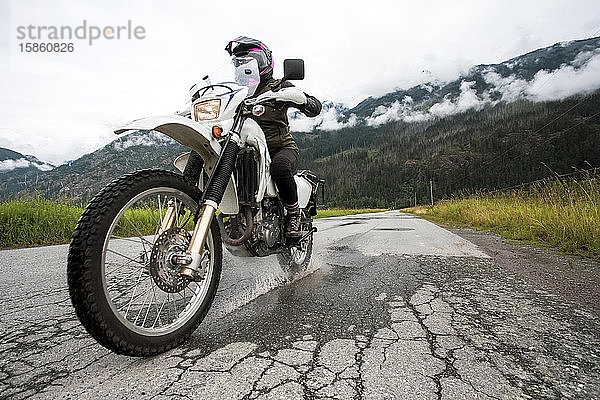 Eine Frau fährt mit ihrem Motorrad an einem bewölkten Sommertag.