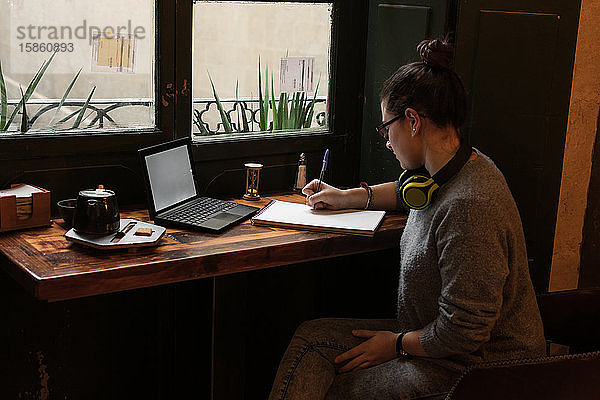 Junge Studentin lernt mit ihrem Laptop in einem Café