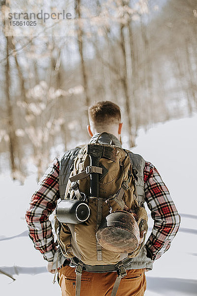 Nahaufnahme eines Mannes mit Rucksack und Flanell in schneebedeckten Wäldern