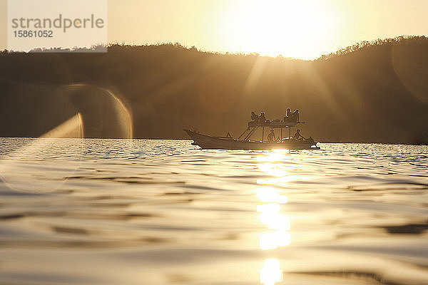 Gruppe von Personen auf dem Boot zur Zeit des Sonnenuntergangs