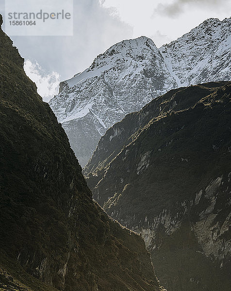 Ein schneebedeckter Berg überragt steile zerklüftete Canyonwände in Neuseeland
