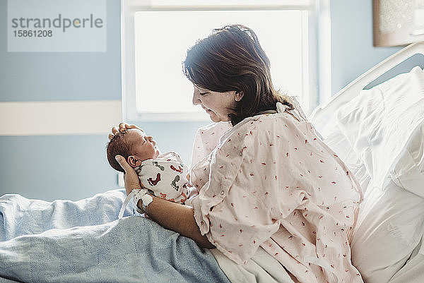 Seitenansicht der Mutter  die den neugeborenen Sohn im Krankenhaus liebevoll ansieht