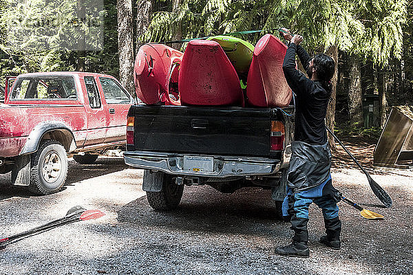 Ein Mann belädt Wildwasserkajaks auf der Ladefläche eines Pickup-Trucks.