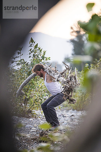 fitter Mann  der einen umgefallenen Baum benutzt  um eine Hocke im Freien zu vollenden.