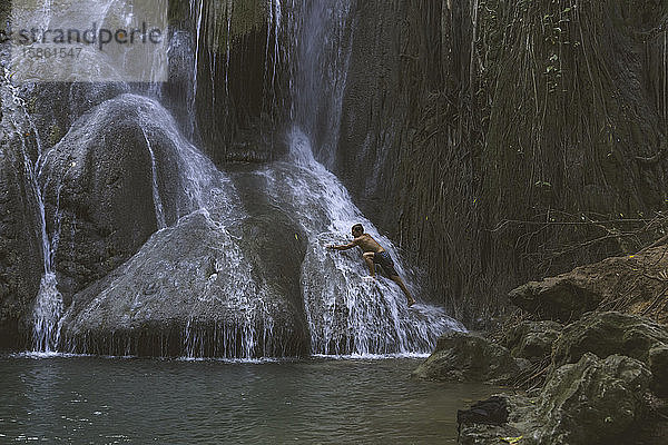 Mann steht unter Wasserfall