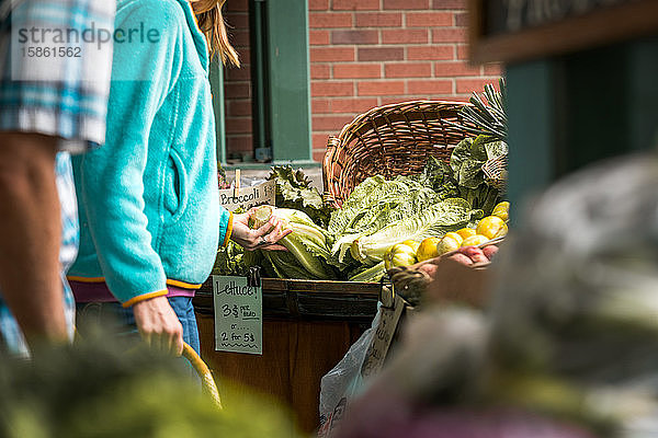 Frau auf dem Bauernmarkt betrachtet Greens