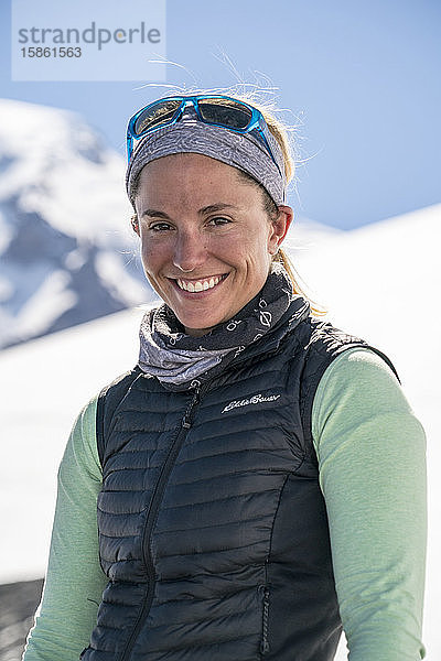 Porträt einer lächelnden Bergsteigerin mit Mt. Baker im Hintergrund