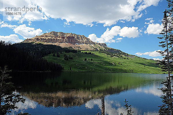 Rocky Mountain spiegelt sich im See mit aufgeblasenen weißen Wolken und blauem Himmel