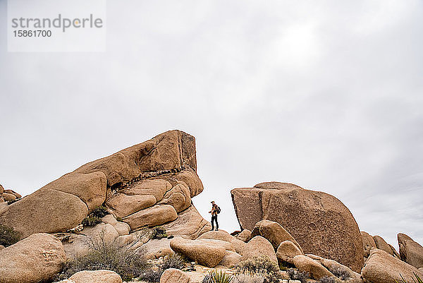 Mann zwischen seltsamen Felsformationen in der Wüste unter grauem Himmel