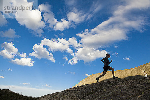 Mann rennt als Silhouette in Indian Peaks Wilderness  Colorado  auf einen Felsen