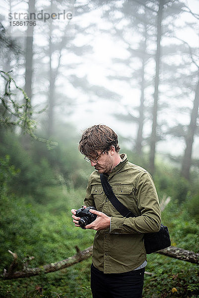 Fotograf schaut auf die Kamera im Freien im Wald