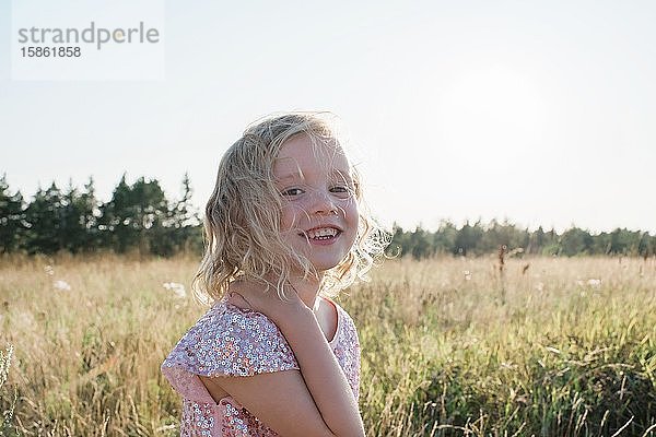 Porträt eines jungen Mädchens  das bei Sonnenuntergang mit einem funkelnden Kleid lächelt