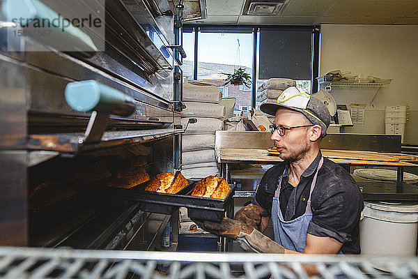 Die obere Hälfte der professionellen Bäcker zieht Brotlaibe aus dem heißen Ofen