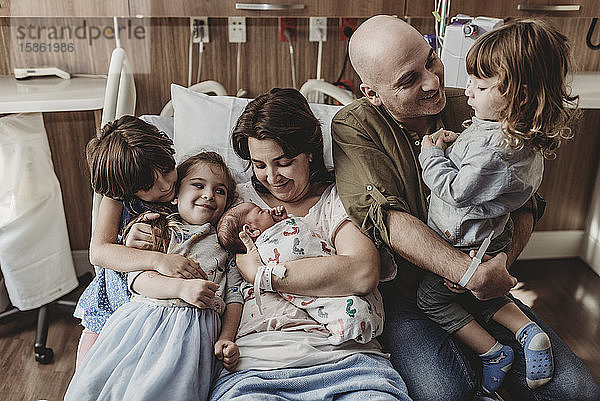 Mittelansicht der ganzen Familie  die den neugeborenen Sohn im Krankenhaus hält
