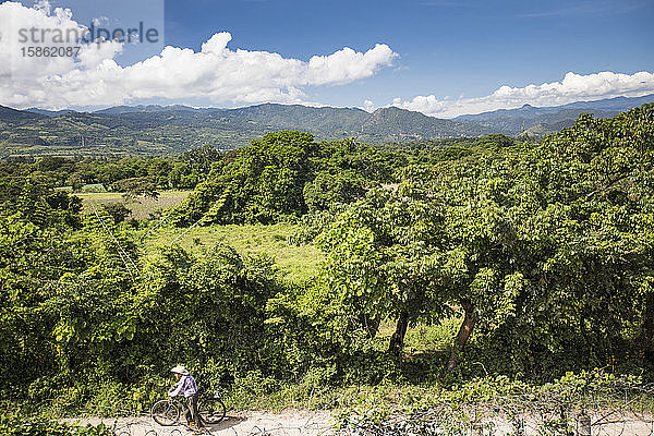 Älterer Mann schiebt Fahrrad auf Feldweg  Guatemala.