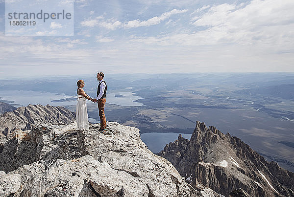 Braut und Bräutigam halten Händchen  nachdem sie auf dem Berggipfel geheiratet haben