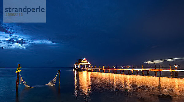 Nachtpieransicht auf das Meer beleuchtet mit Hängematte auf dem Wasser