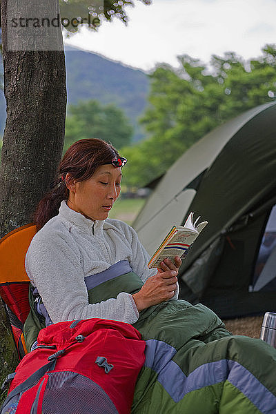 Frau  die auf dem Campingplatz ein Buch liest