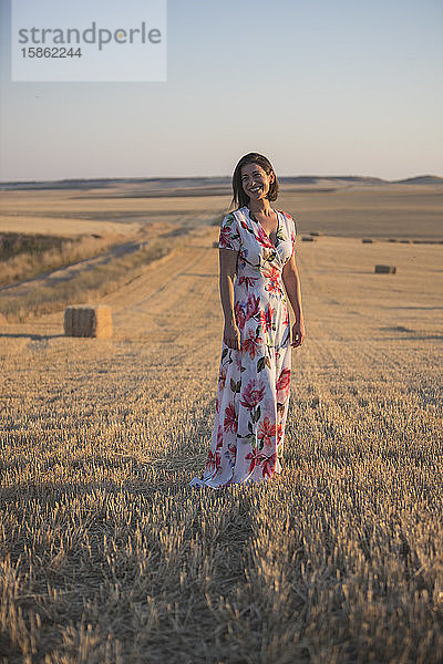 Frau  die das trockene Feld bei Sonnenuntergang beobachtet