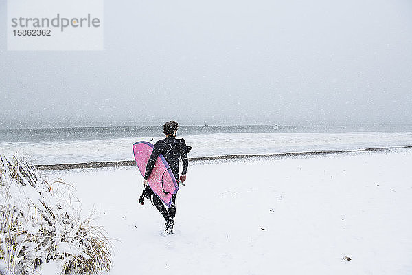 Mann geht im Winterschnee surfen