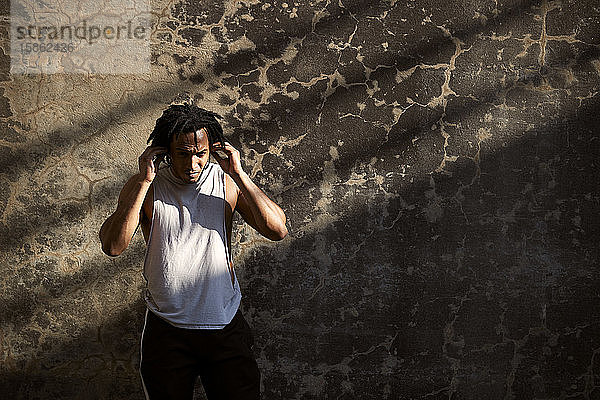 Afroamerikanischer Mann beim Anpassen von Ohrstöpseln im Freien