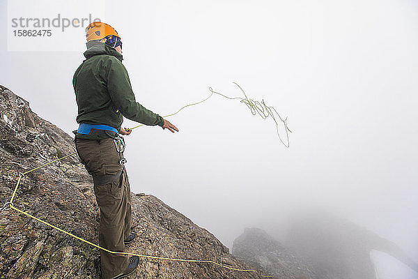 Bergsteiger wirft Kletterseil über den Rand einer Klippe