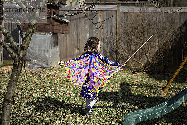 Ein glückliches Kind rennt im Frühling mit Schmetterlingsflügeln durch einen Garten