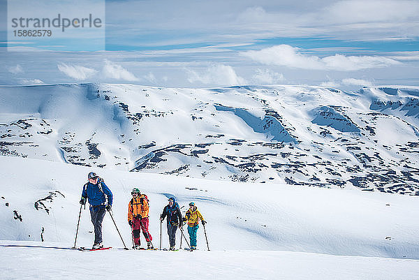 Eine Gruppe von Skifahrern auf Tournee in verschneiten Bergen in Island