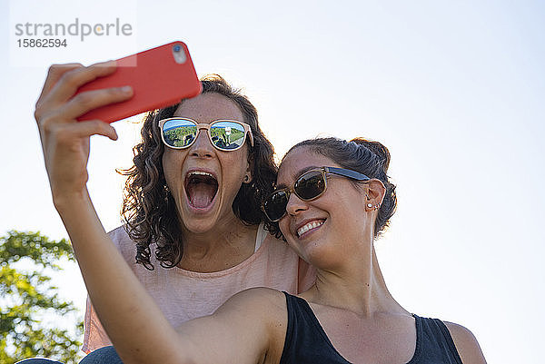 Zwei Freundinnen  die für einen Selfie lächeln