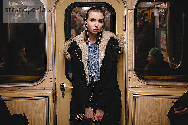 Junge Frau  die in der U-Bahn mit Kopfhörern Musik hört