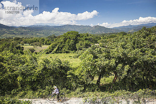 Älterer Mann schiebt Fahrrad auf Feldweg  Guatemala.