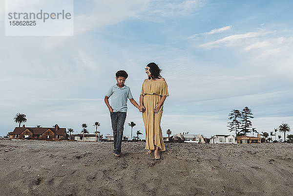 Junge Mutter und schulpflichtiger Sohn stehen auf Stranddüne