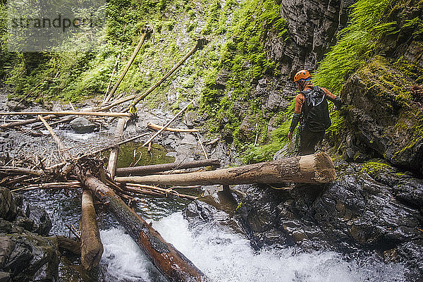 Wanderer klettert eine steile Klippe neben einem Wasserfall hinunter.