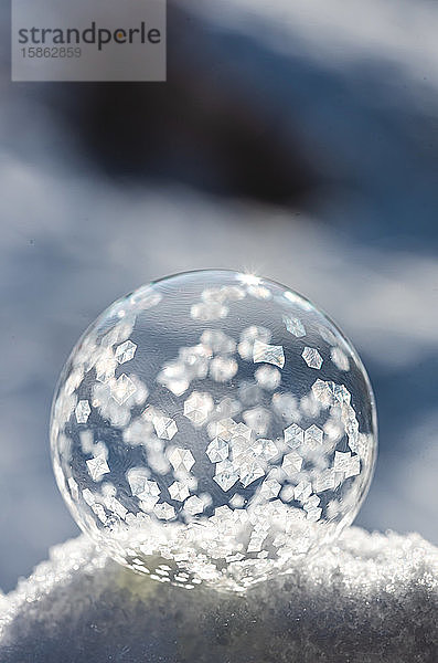Nahaufnahme einer Seifenblase  die an einem Wintertag im Schnee gefriert.