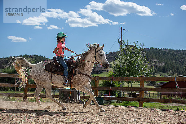 Mädchen reitet auf einem Pferd in der Reithalle