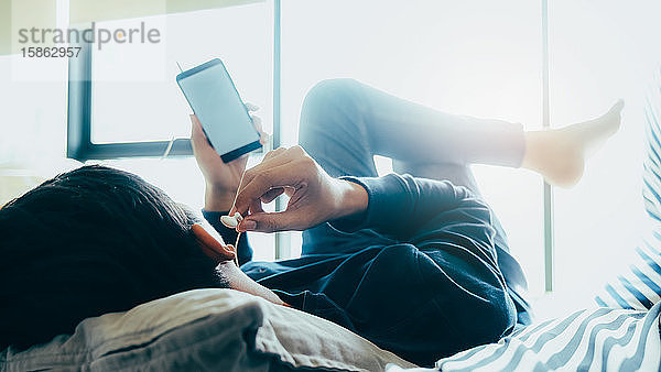 Junger Mann entspannt sich beim Hören der Musik vom Mobiltelefon aus.